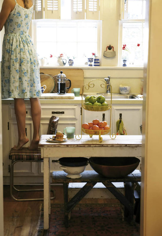 An old sewing table-turned-kitchen-island anchors a petite and sunny cookspace.  